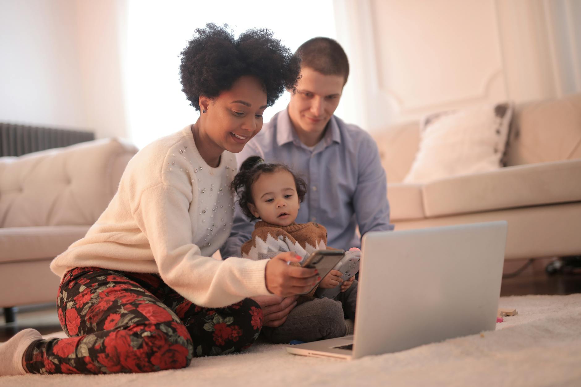 photo of woman using smartphone while sitting near her baby